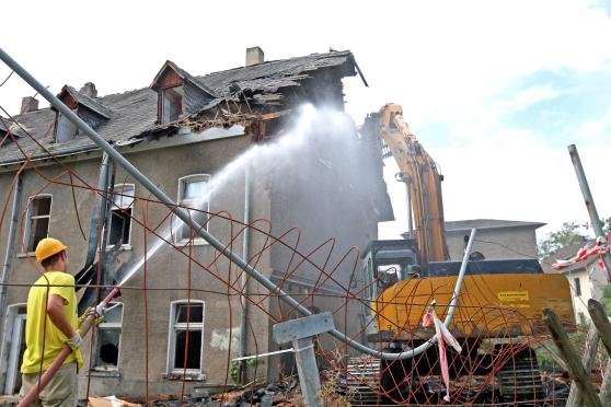 Um Staubwolken beim Abriss des Steinhauses zu vermeiden, spritzte ein Arbeiter Wasser auf die Mauern. FOTO: CARINA WESTERWELLE