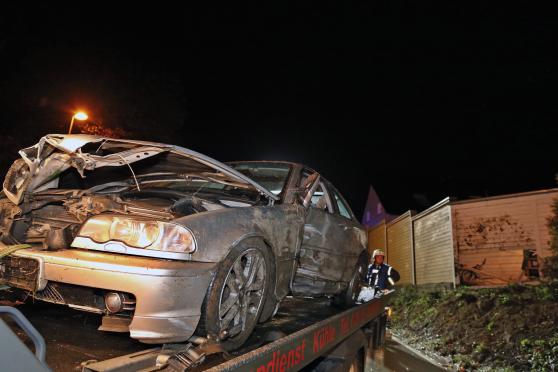 Der havarierte Pkw auf dem Abschleppfahrzeug – im Hintergrund das Carport mit dem Unfallschaden – Der Unfallverursacher war die Hauptstraße in Richtung Werl und dann die Böschung hinauf gefahren bevor er die Holzwand durchbrach. FOTO: ANDREAS DUNKER