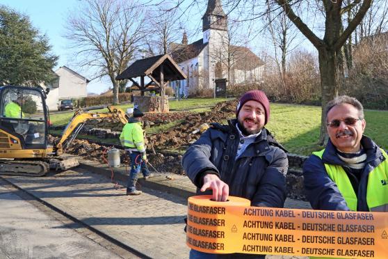 Bauleiter Achmed Canikli (links) vom Straßen- und Tiefbauunternehmen „SGK“ aus Hamm und Bauleiter Bahman Jalilehvand (recht) von „Deutsche Glasfaser“ präsentierten das sogenannte Trassenband mit der Aufschrift „ACHTUNG KABEL DEUTSCHE GLASFASER“ FOTO: ANDREAS DUNKER