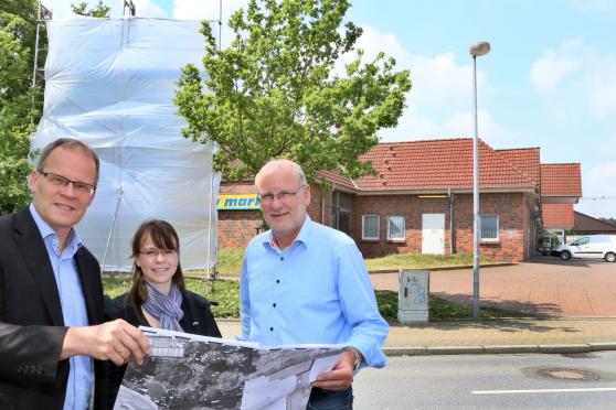 Bürgermeister Dr. Martin Michalzik (CDU) sowie Stephanie Lebusa und Fachbereichsleiter Markus Kleindopp vom Bauamt der Gemeinde Wickede (Ruhr) mit Plänen für den neuen EDEKA-Markt. Im Hintergrund ein Baugerüst mit Plane, welches die Höhe des Gebäudes darstellen soll. ARCHIVFOTO: ANDREAS DUNKER
