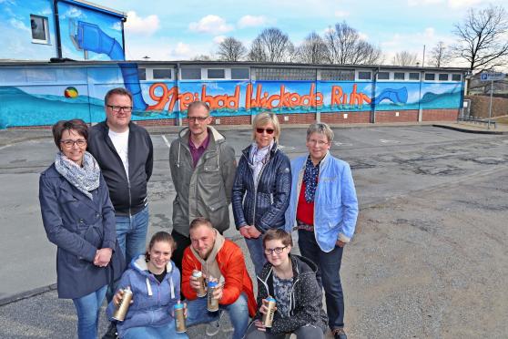 Offizielle Präsentation der mit Graffiti-Kunst verschönerten westlichen Fassade am Freibad der Gemeinde Wickede (Ruhr). Vordere Reihe, von links: Schülerin Lilli Knop, Grafitti-Künstler Patrick Sziedat aus Herne-Wanne und Schülerin Klara Dämgen mit Farbspraydosen. Hintere Reihe, von links: die Sponsoren-Vertreter Antje Kuss von der Sparkasse SoestWerl und Ralf Hettwer als Vorsitzender des Fördervereins des Freibades Wickede (Ruhr) sowie Schwimmmeister Michael Scheffler, die verantwortliche Sachbearbeiterin Ruth Hornkamp aus dem Rathaus und die stellvertretende Bürgermeisterin Gertrud Martin (CDU) von der Gemeinde Wickede (Ruhr). FOTO: ANDREAS DUNKER 