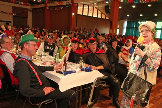 „Käthe aus Wiehagen“ (Gudrun Arndt) mit ihrem „Wägelsken“ (Rollator) am Tisch mit den Ehrengästen. Darunter Pfarrer Thomas Metter mit Mutter, Bürgermeister Dr. Martin Michalzik (CDU) mit Gattin Martina sowie der evangelische Pfarrer Dr. Christian Klein mit seiner Gattin Sylvia Klein-Hölscher. FOTO: ANDREAS DUNKER
