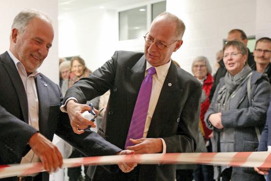 Diplom-Bauingenieur Andreas Ersel (links) und Pfarrer Dr. Christian Klein (rechts) schnitten gemeinsam das rot-weiße Flatterband durch, welches symbolisch den Durchgang zum großen Saal des Martin-Luther-Hauses versperrte. FOTO: ANDREAS DUNKER