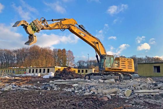 Während im Hintergrund noch Arbeiter händisch mit dem Rückbau der ehemaligen Mannschaftsunterkünfte beschäftigt sind, streckt im Vordergrund ein Kettenbagger seine Abbruchzange in die Luft. FOTO: ANDREAS DUNKER