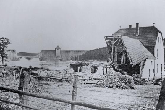 Die zerstörte Möhnetalsperre nach ihrer Bombardierung in der Nacht vom 16. auf den 17. Mai 1943 – im Vordergrund ein zerstörtes Haus ARCHIVFOTO