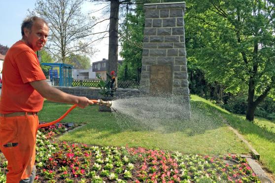 Bauhofmitarbeiter Siegfried Gebhardt gießt die frisch angepflanzten Blumen am Mahnmal zu Ehren der Opfer der Möhnekatastrophe am Ruhrufer. FOTO: ANDREAS DUNKER