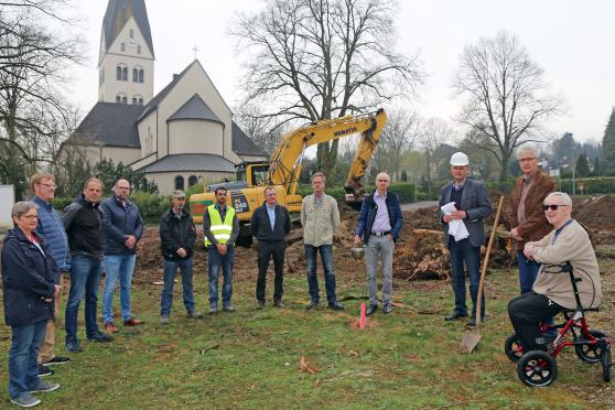 Katholische Geistliche, Kirchenvorstandsmitglieder und Bauleute beim symbolischen ersten Spatenstich im Rahmen des Pfarrheim-Neubaus an der Friedhofstraße (von links): Lydia Münstermann, Vikar Alexander Plümpe, Architekt Stephan Voß vom Mendener Architekten- und Ingenieur-Büro „Hilker + Jochheim“, Dirk Heggemann (Ziegelei-Vertreter), Erich Brumm und André Gomes vom Tiefbau-Unternehmen Driller, Guido Laarmann–Quante, Bernd Stute, Franz–Josef Schulte, Pfarrer Thomas Metten (mit Stola und Sturzhelm), Peter Hesse und Horst-Dieter Pieper. Im Hintergrund: die katholische St.-Antonius-Pfarrkirche. FOTO: ANDREAS DUNKER 