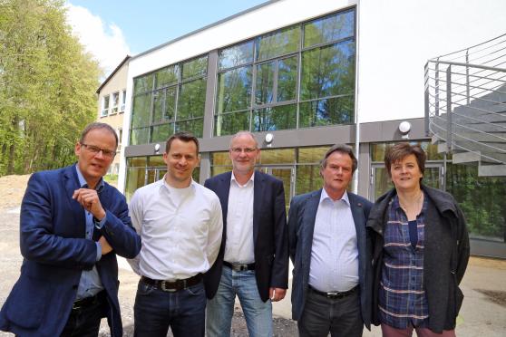 Die Fensterfront des neuen Forums bietet schöne Aussichten in den benachbarten Erbke-Wald. – Von links: Bürgermeister Dr. Martin Michalzik (CDU) und Sekundarschulleiter Jan Haurand sowie Fachbereichsleiter Markus Kleindopp, Frank Knop vom Bauamt und Susanne Modler vom Schulamt der Gemeindeverwaltung. FOTO: ANDREAS DUNKER
