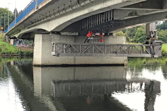 Monteure befestigen derzeit die Verstärkungselemente aus Metall unter der Spannbetonbrücke aus den 1960-er Jahren. Dabei schwebt die große Arbeitsbühne, die von oben gehalten wird, über der Ruhr. FOTO: ANDREAS DUNKER