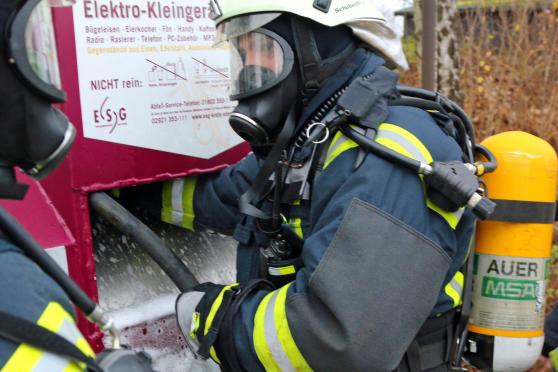 Ein Feuerwehrmann flutet den qualmenden Container mit Löschschaum. FOTO: ANDREAS DUNKER