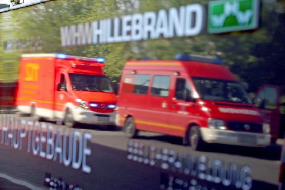 Ein Rettungsdienst- und ein Feuerwehr-Fahrzeug spiegeln sich im Firmenschild der Firma WHW Hillebrand FOTO: ANDREAS DUNKER